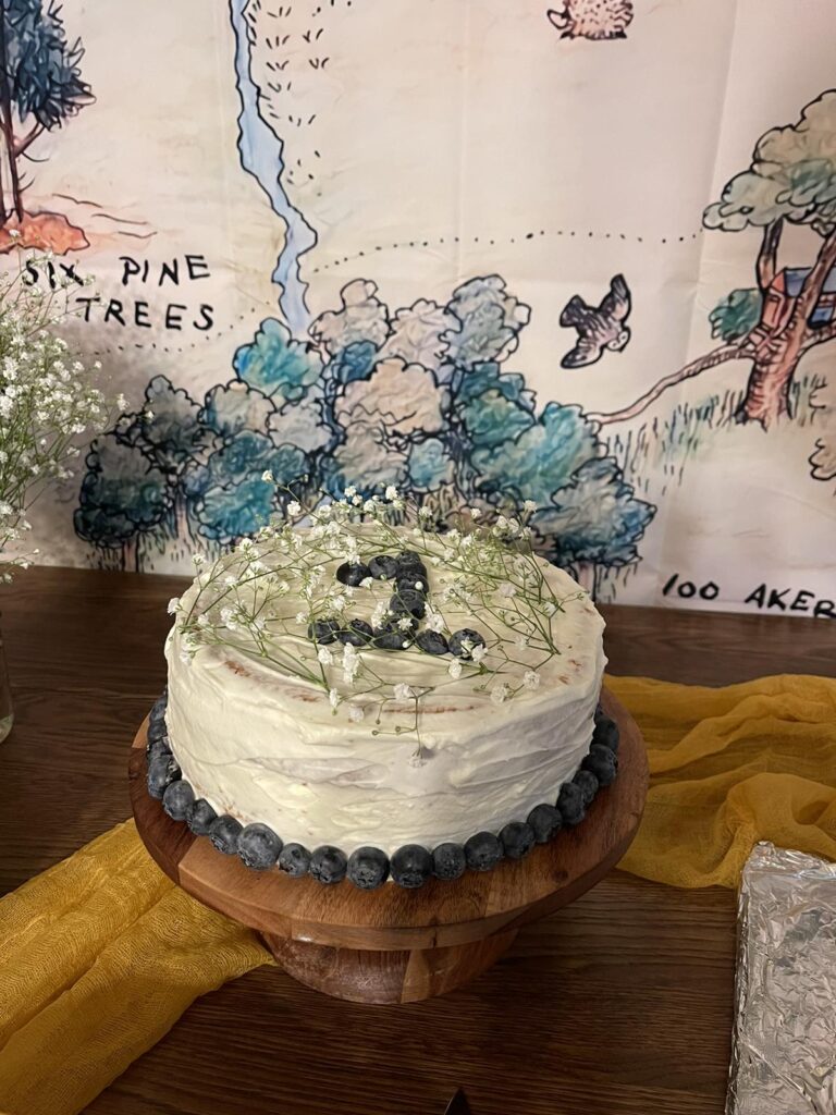 white cake with baby's breath and blueberries on wooden cake stand