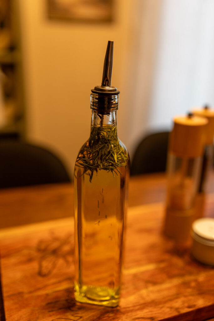 glass jar of herb-infused olive oil standing on table