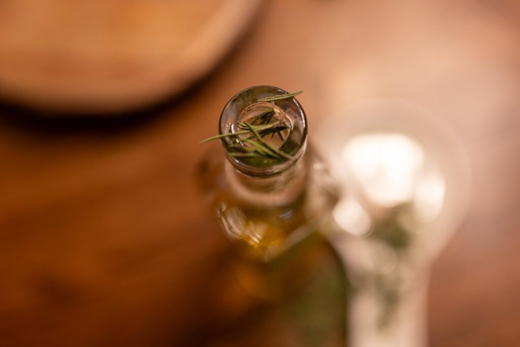 placing rosemary into the jar of olive oil