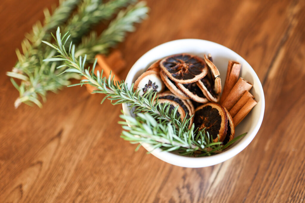 rosemary sprigs, dried oranges, and cinnamon sticks in a bowl