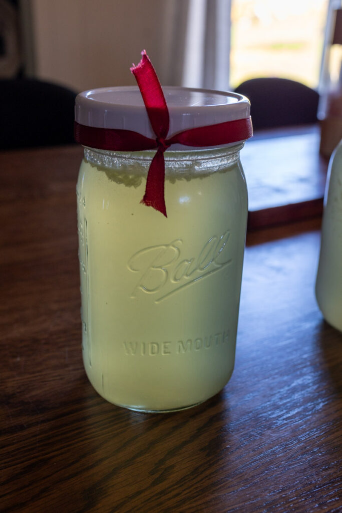 a mason jar of bone broth with a red ribbon tied to it