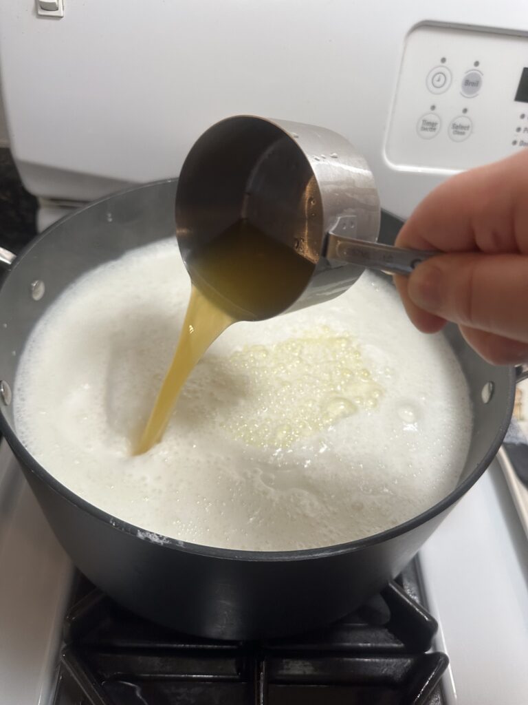 lemon juice pouring into pot of milk
