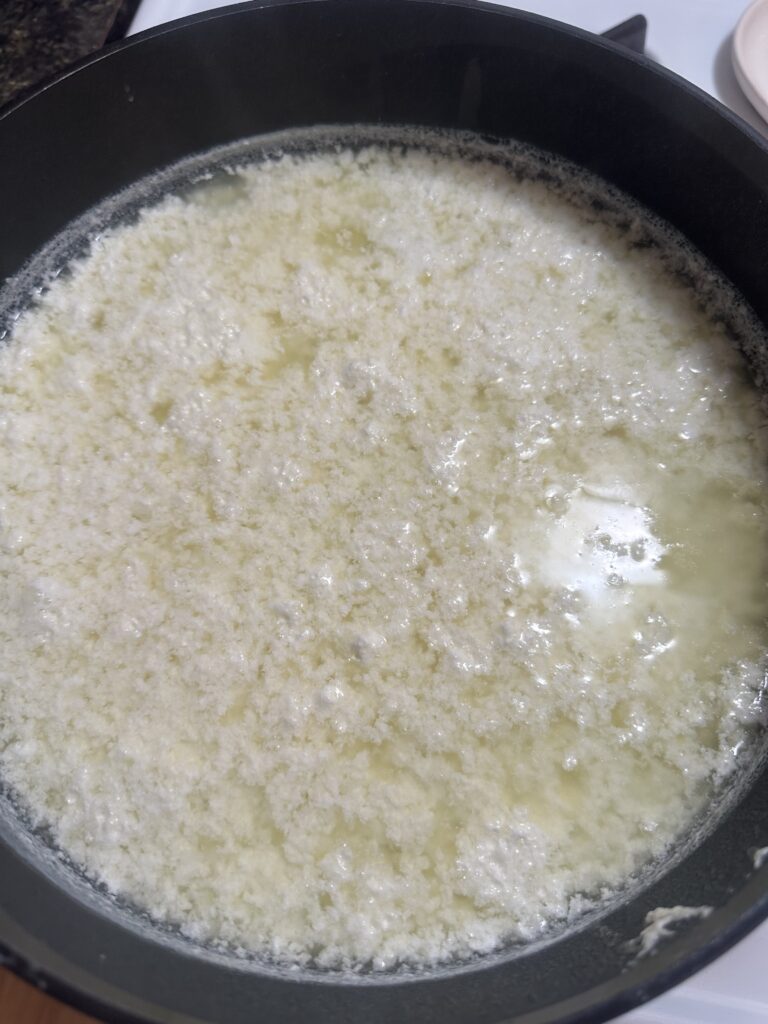 homemade cottage cheese in a pot not yet separated from the whey