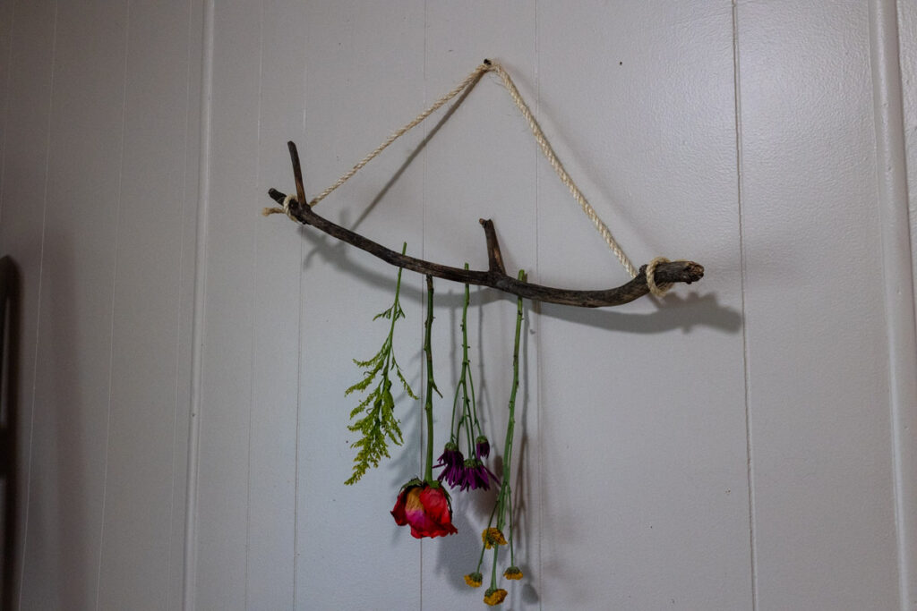 process of tying flowers on a branch to dry
