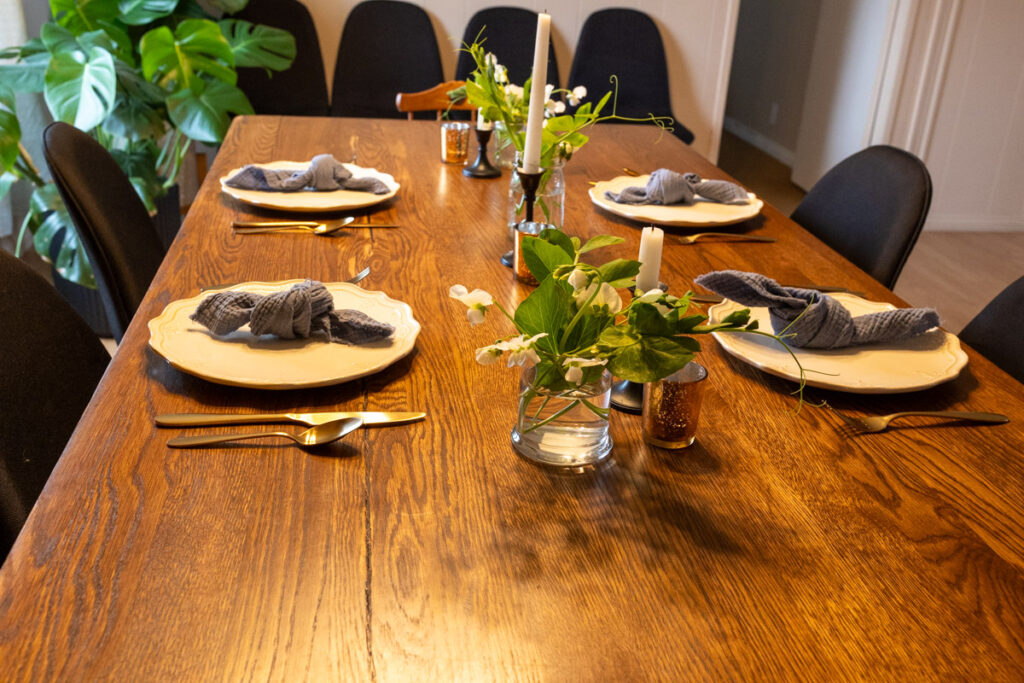 table decorated with bouquets of sweet pea flowers, white dishes, and golden silverware