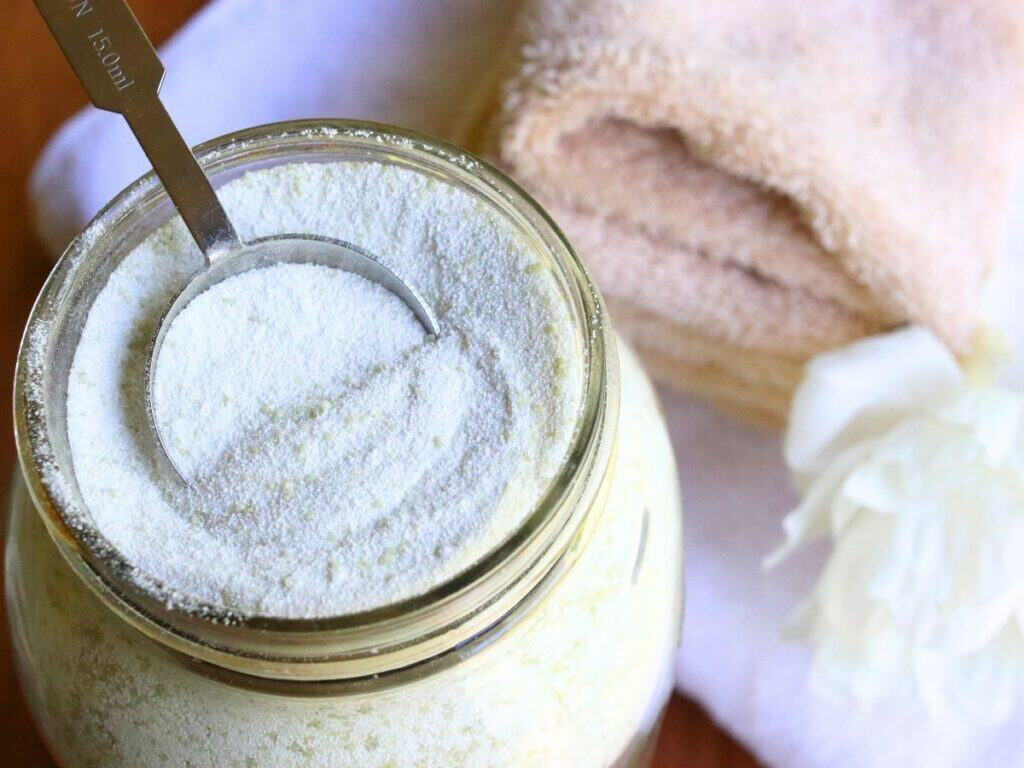 powdered laundry detergent in a jar and measuring spoon in it